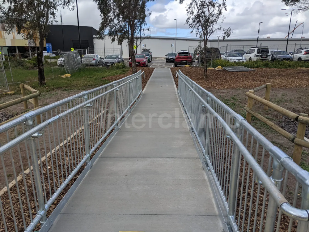 Interclamp pedestrian barriers and key clamp DDA assist rail creating a secure waiting area at a bus stop, preventing pedestrian accidents.